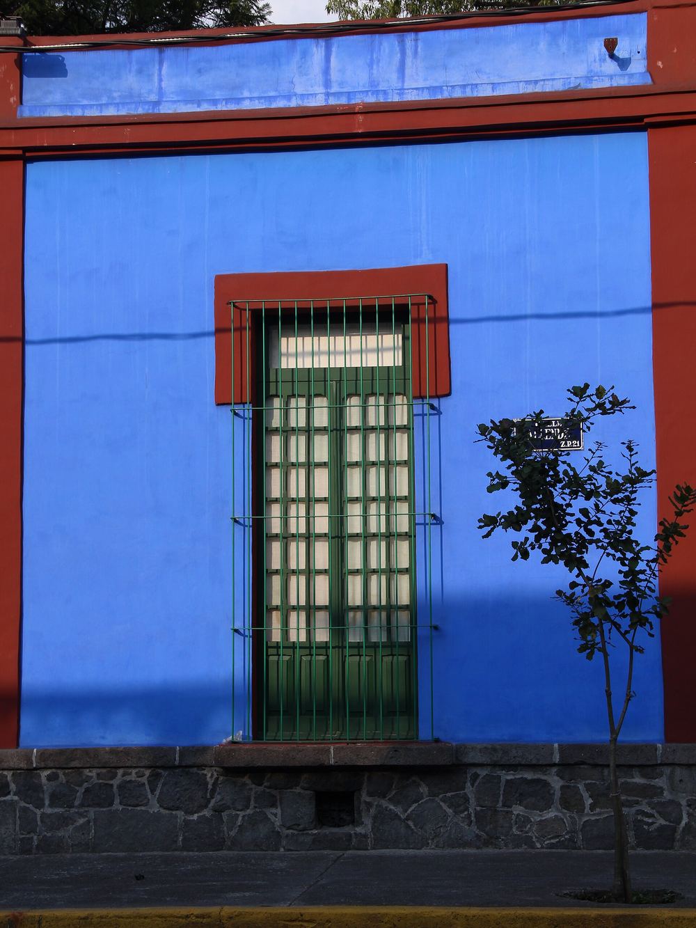 Una ventana con persianas verdes en la pared azul cobalto de la Casa Azul