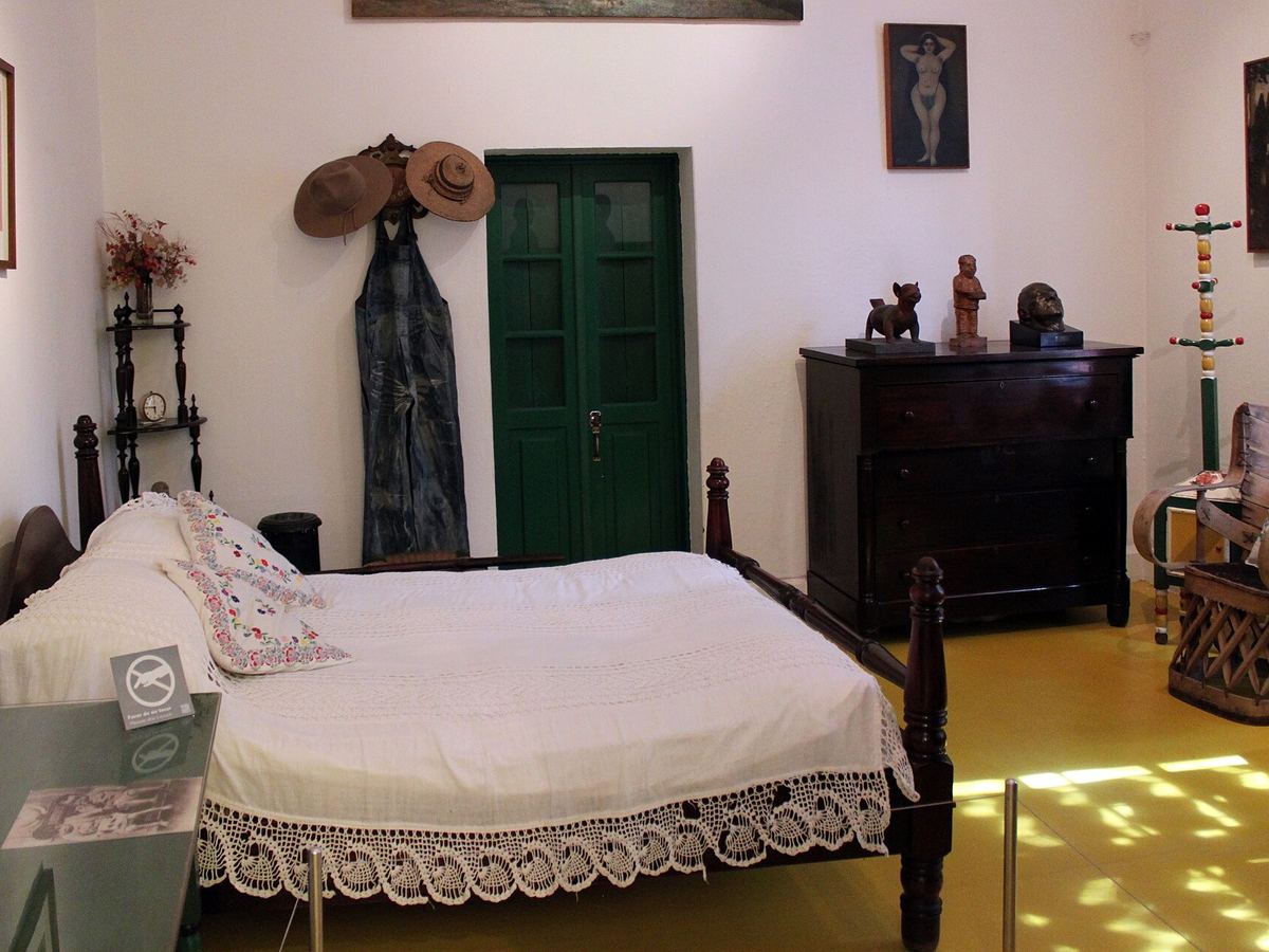 Un dormitorio en la Casa Azul con una cama tallada y artesanías mexicanas