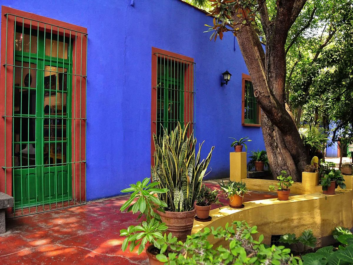 Paredes azul cobalto y ventanas verdes del patio de la Casa Azul